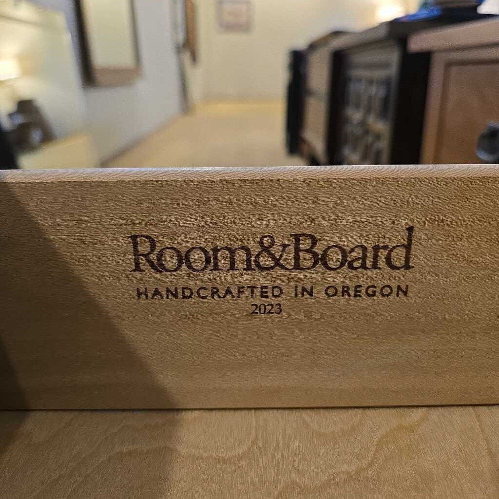 Wooden box with 'Room & Board Handcrafted in Oregon 2023' engraving on a blurred background.