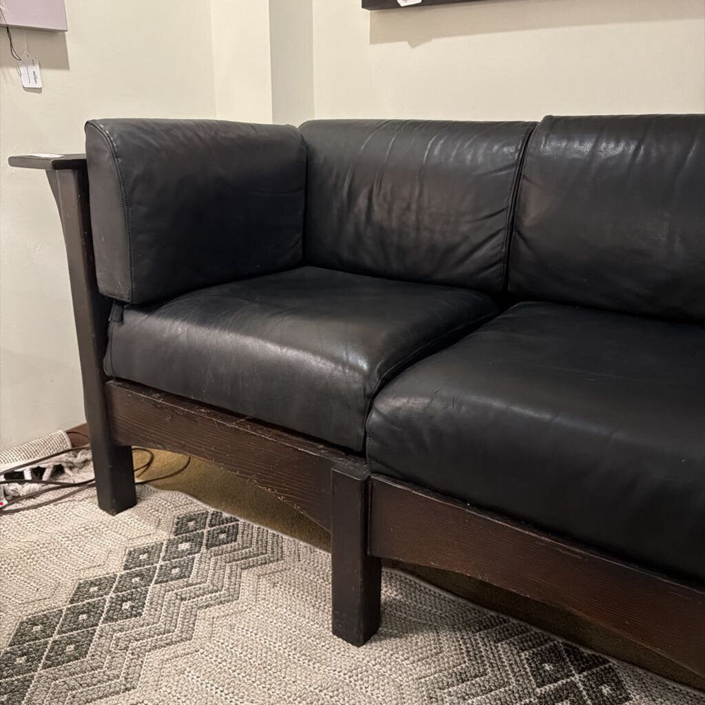 Black leather sectional sofa in a room with a patterned rug.