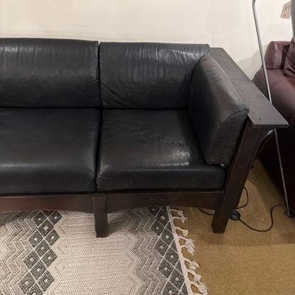 Black leather sectional sofa in a room with a patterned rug.