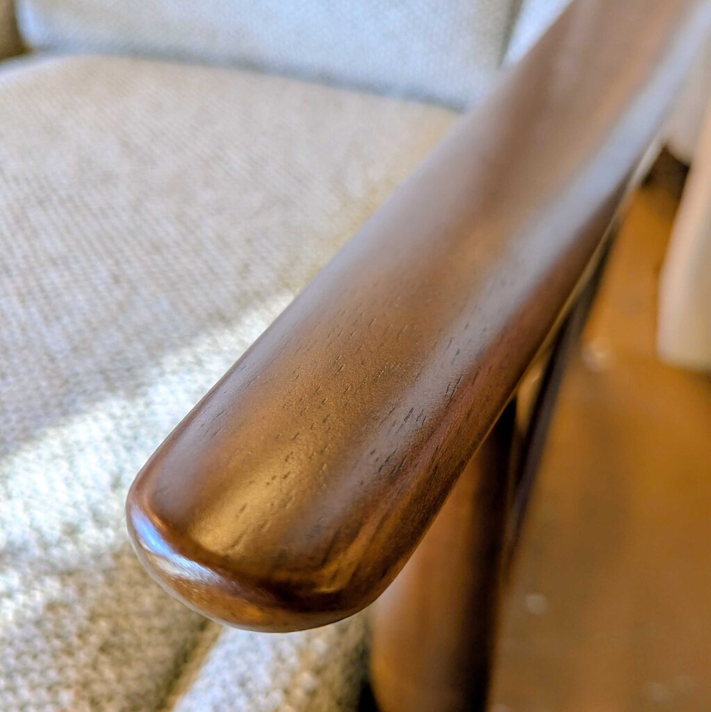 Close-up of a wooden armrest on a chair with a blurred background