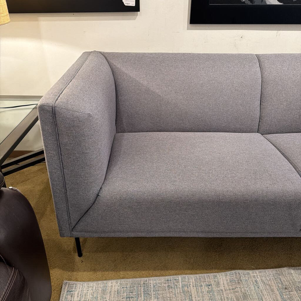 Gray sofa in a room with a rug and furniture.