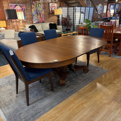 Wooden dining table with blue chairs in a room with a couch and various decor items.