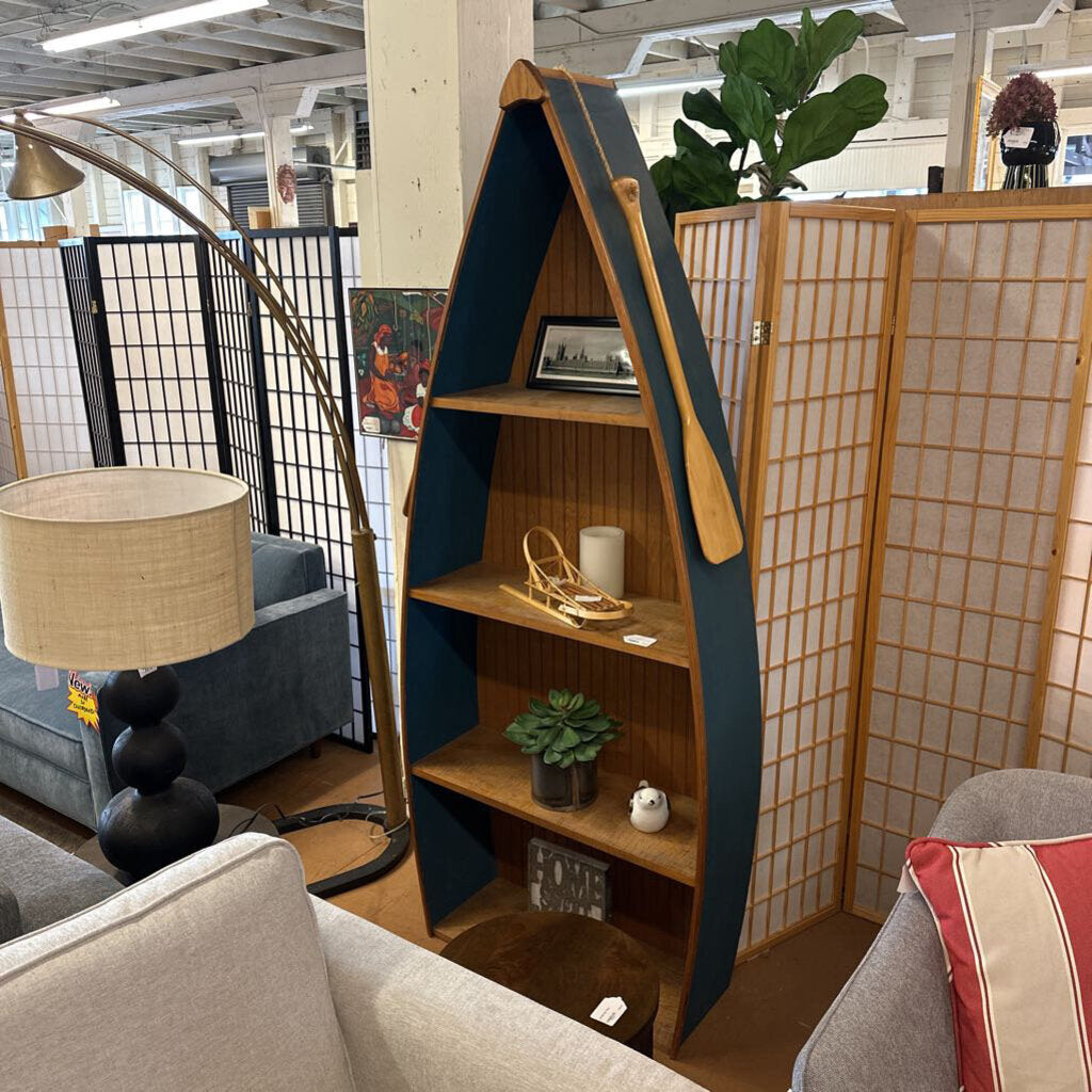 Wooden bookshelf with shelves against a wall in a room with a lamp and sofa.