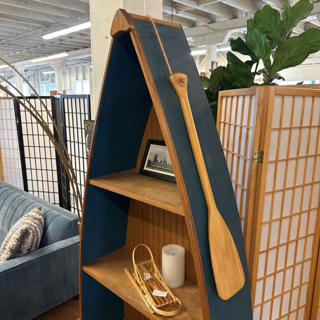 A-frame bookshelf with wooden paddle and decorative items in a room with plants and a couch.