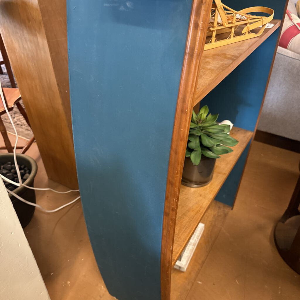 Wooden shelf with a plant against a blue wall in an indoor setting