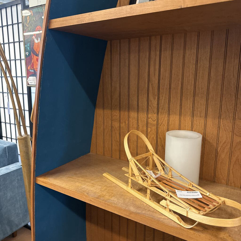 Wooden sled on a wooden shelf with a lamp against a blue wall