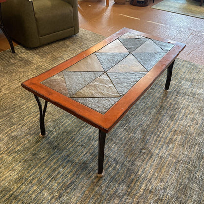 Coffee table with a mosaic tile top in a room with carpeted floor and furniture.