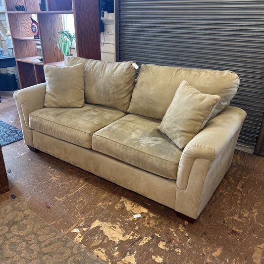 Beige sofa with cushions in a room with a metal shutter door.