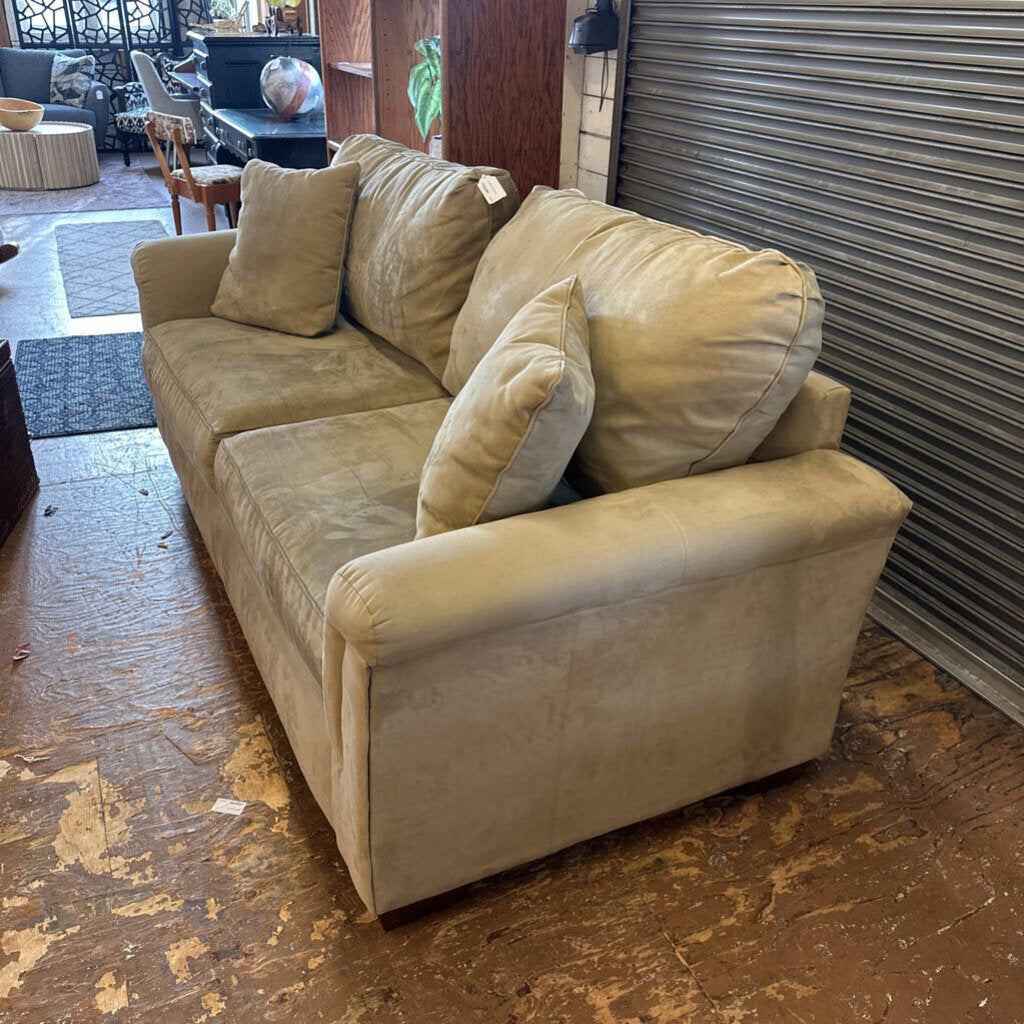 Beige sofa with cushions on a wooden floor in an indoor setting