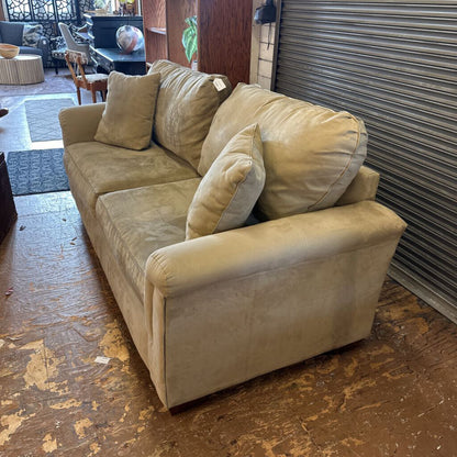 Beige sofa with cushions on a wooden floor in an indoor setting