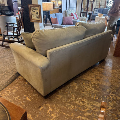 Beige sofa in a room with wooden flooring and other furniture.