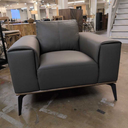 Gray armchair in a showroom setting with furniture and decor in the background