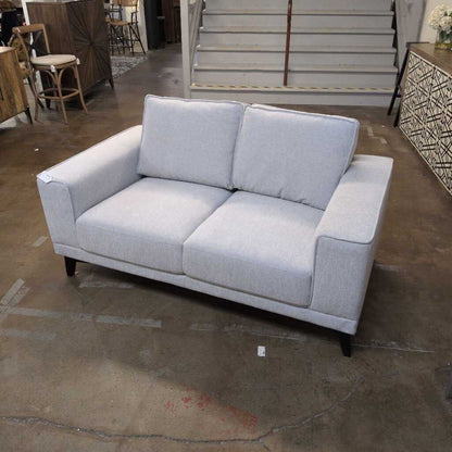 Gray sofa in a room with wooden floor and furniture.