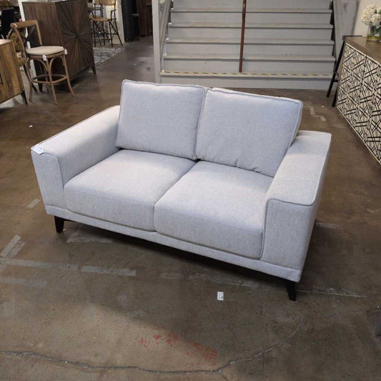 Gray sofa in a room with wooden floor and furniture.