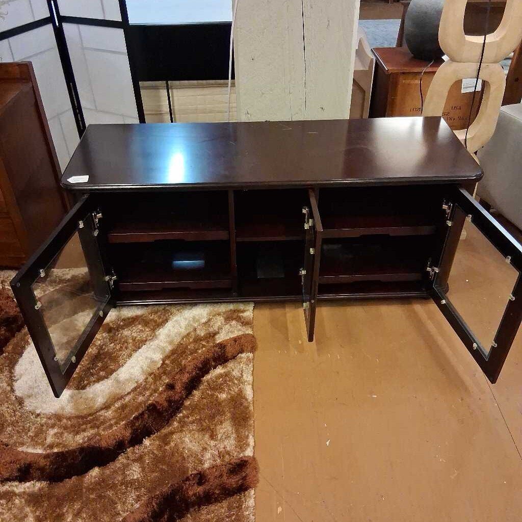 Wooden TV stand with open doors on a brown floor