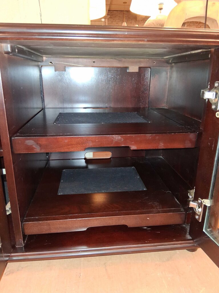 Open wooden cabinet with dark interior and visible hinges.
