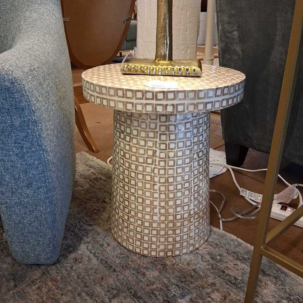 Small round table with a geometric pattern on a carpeted floor.