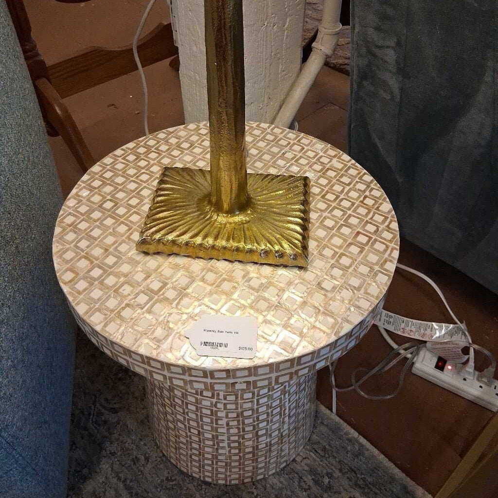 Decorative table with gold base and patterned top in a room setting