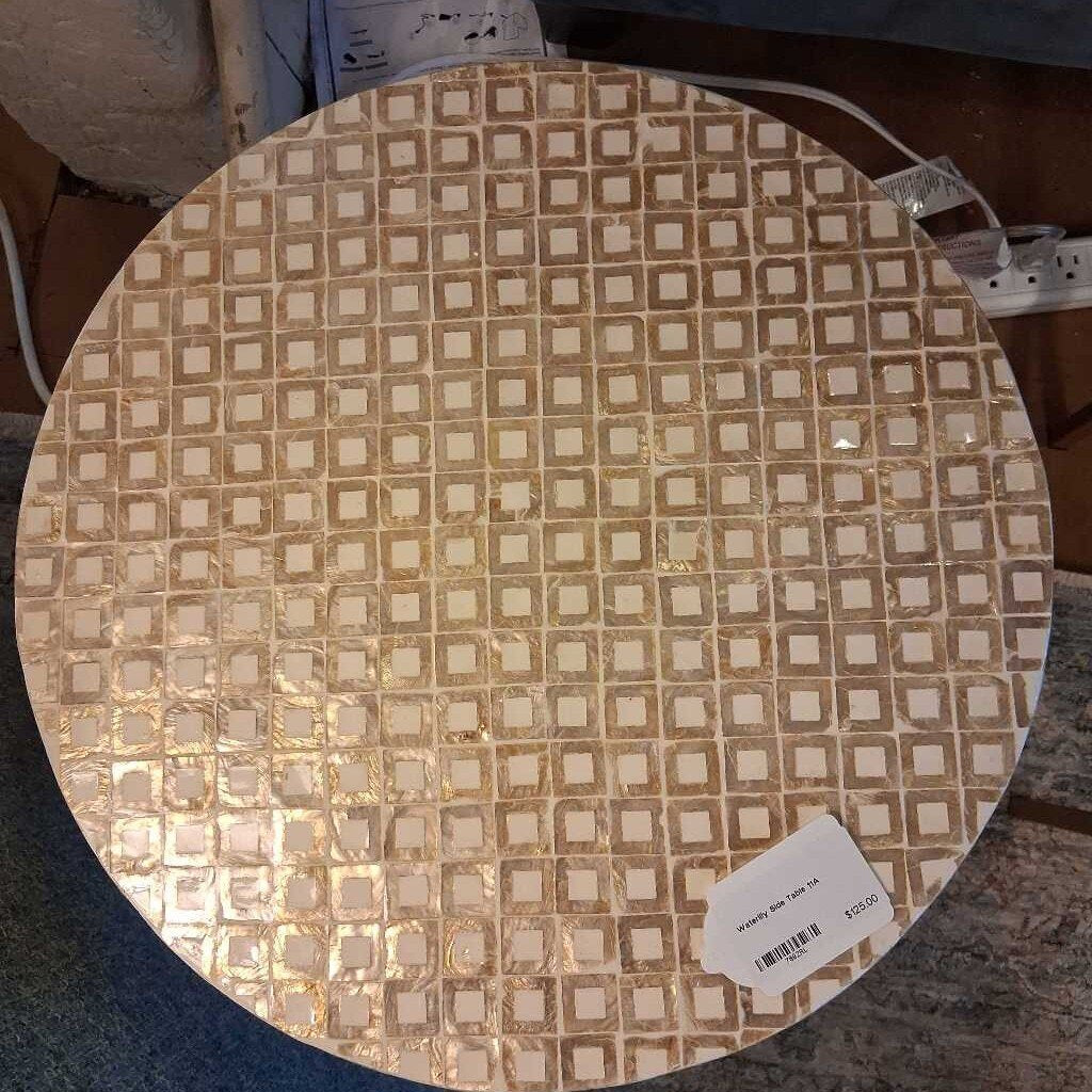 Round table top with square pattern and a visible tag on a carpeted floor.