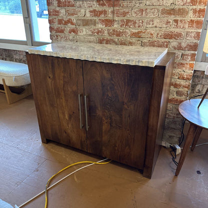 Wooden cabinet with marble countertop against a brick wall