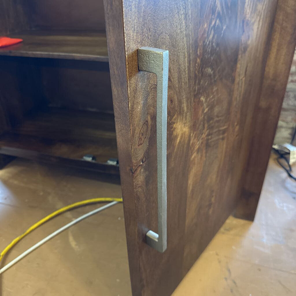 Wooden cabinet with a handle on a concrete floor.