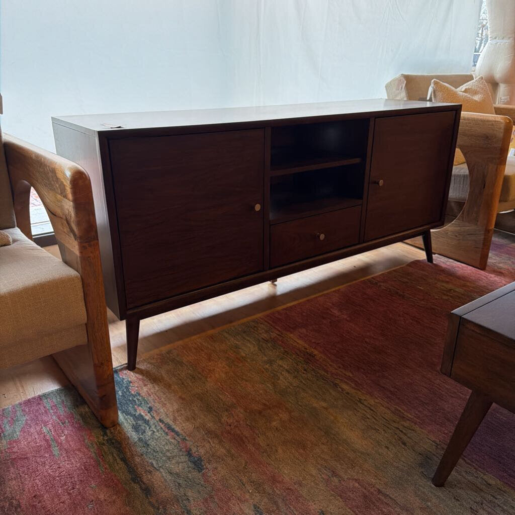 Wooden entertainment console in a living room setting with a rug and chair.