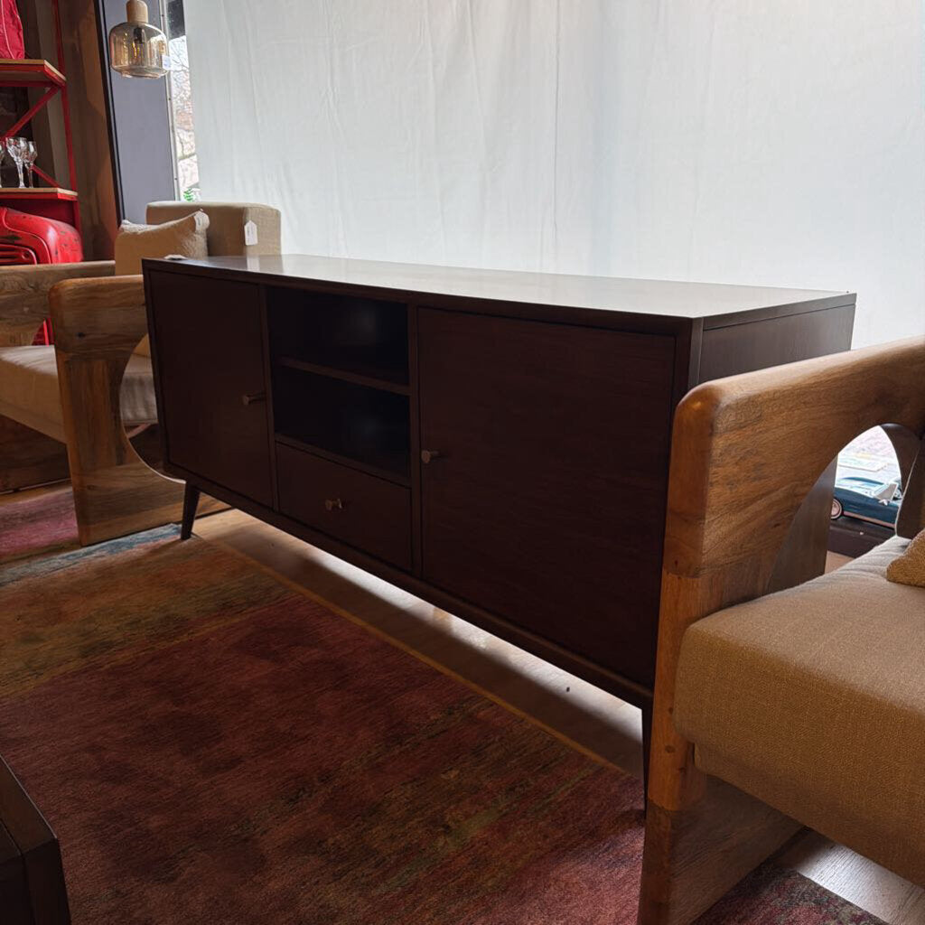 Dark wooden sideboard in a room with wooden chairs and a rug.