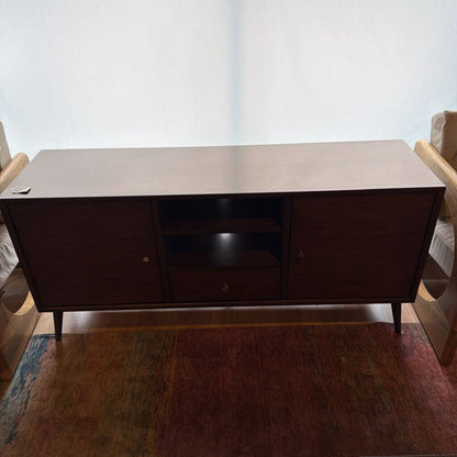 Dark wood TV stand in a living room setting with chairs and a rug.