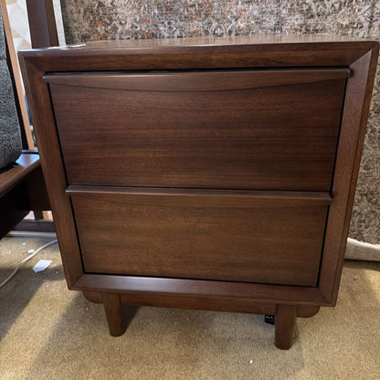 Wooden dresser with two drawers on a carpeted floor.