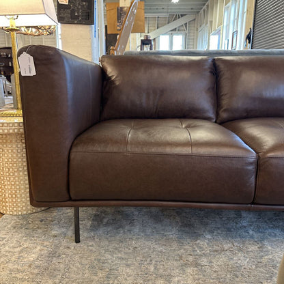 Brown leather sectional sofa in a store setting with a price tag.