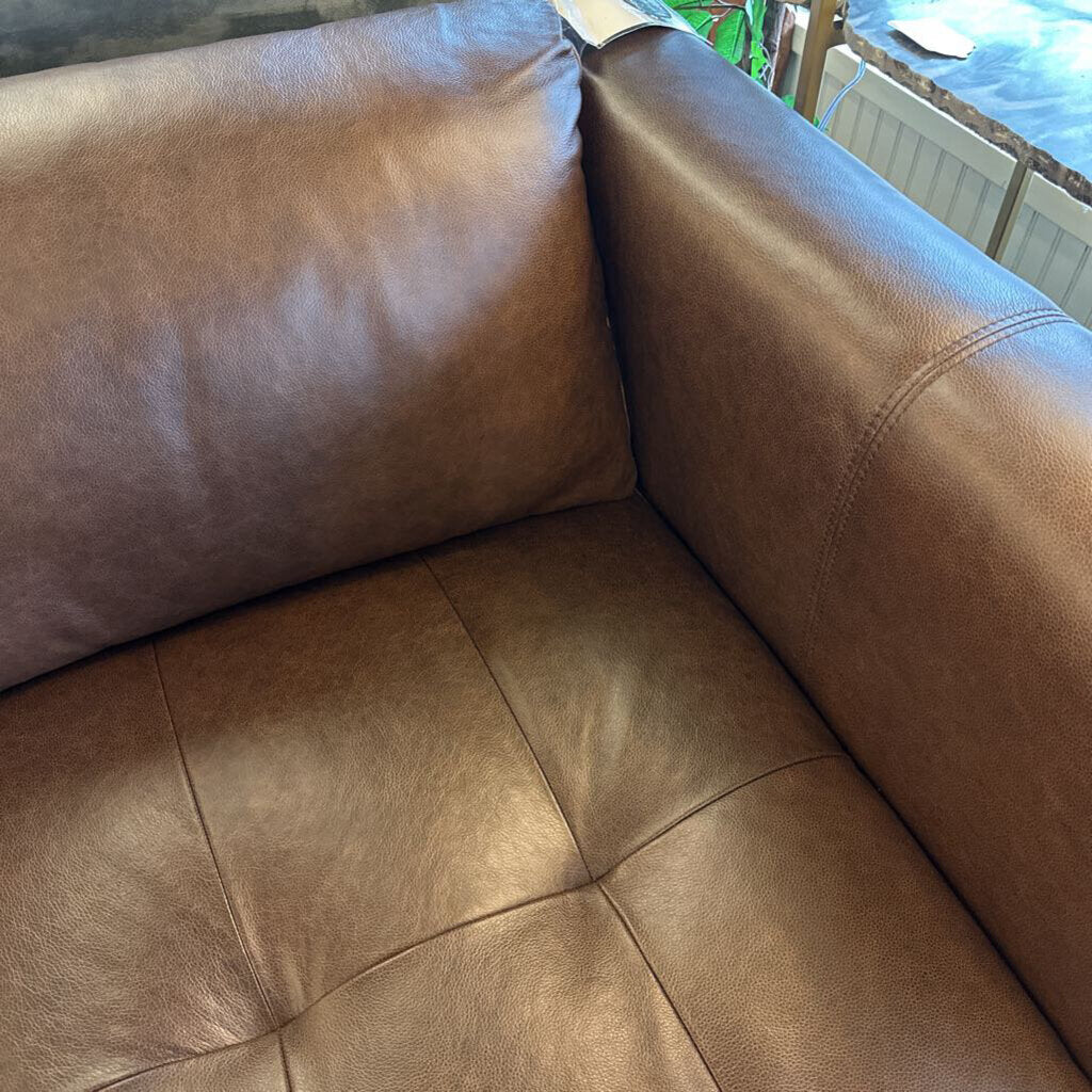 Brown leather sofa in a room with a window and radiator.