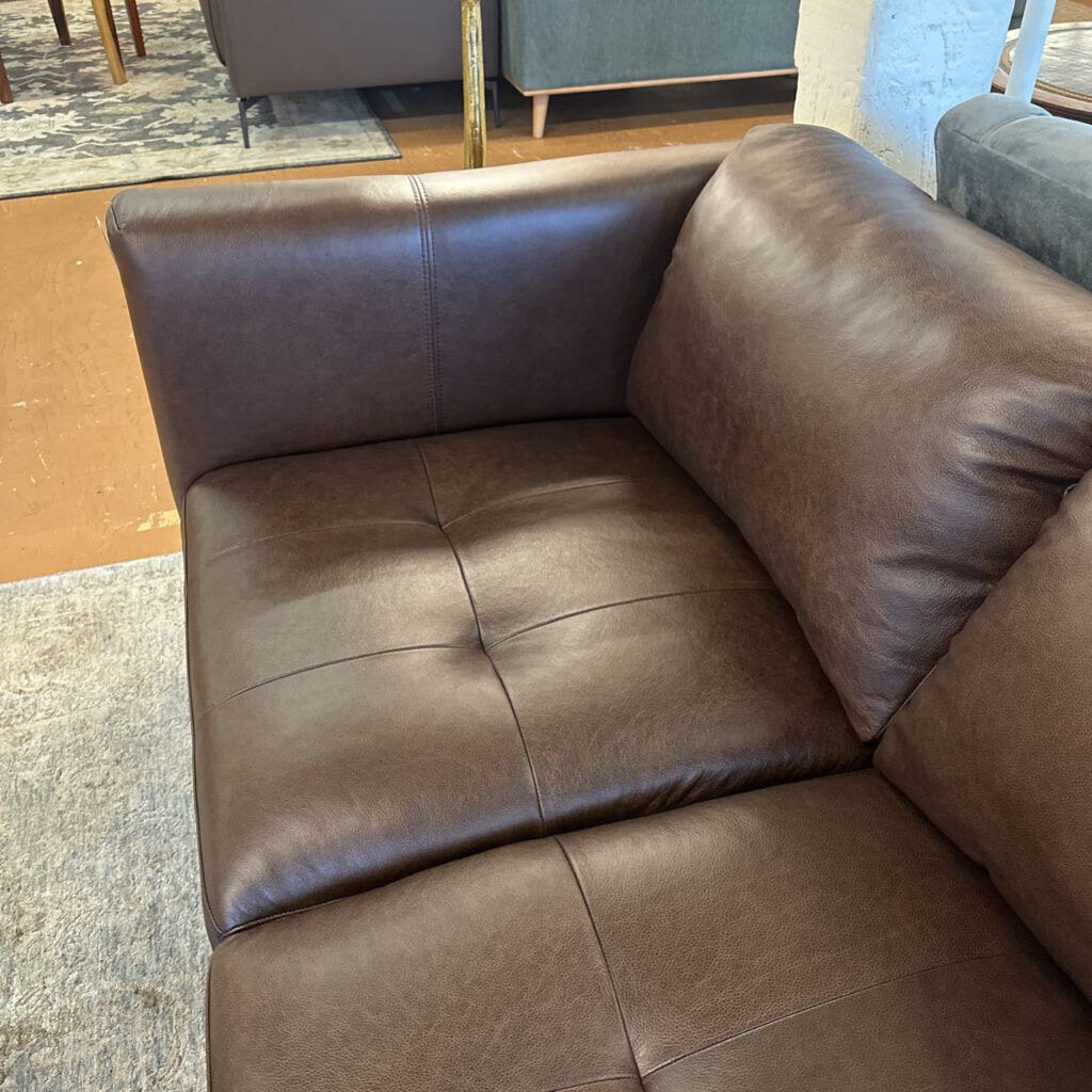 Brown leather sectional sofa in a room with a rug and furniture.