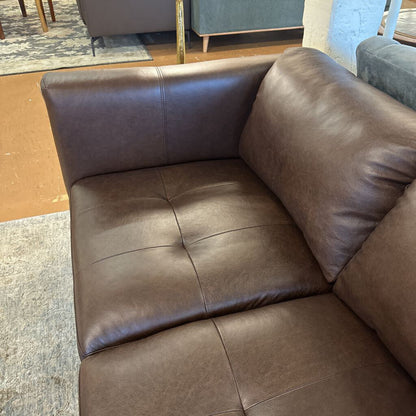 Brown leather sectional sofa in a room with a rug and furniture.