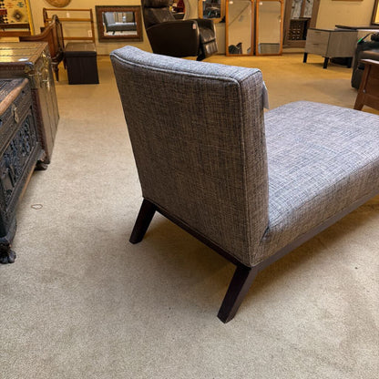 Gray upholstered chair with wooden legs in a showroom setting