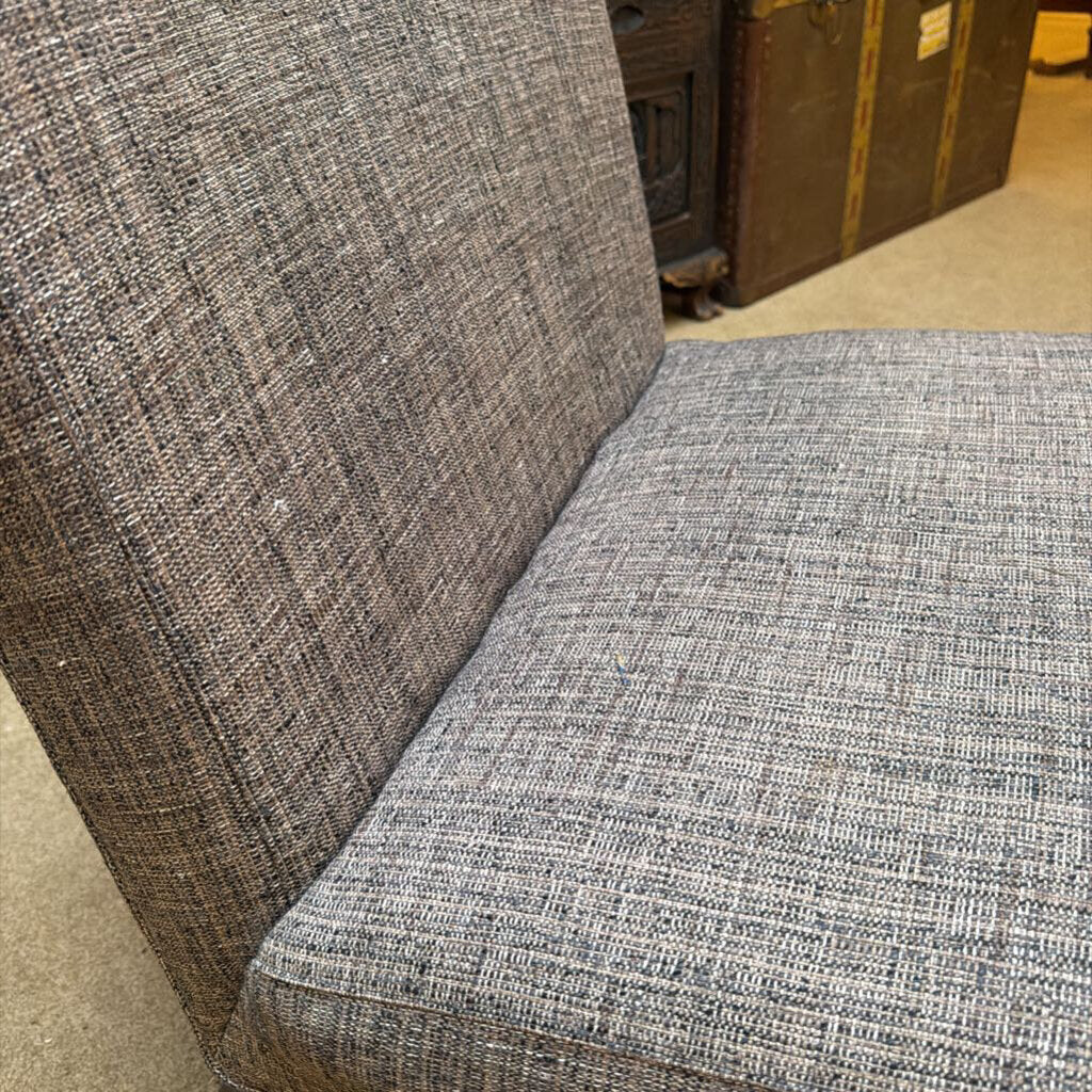 Gray textured fabric on a chair with a wooden trunk in the background