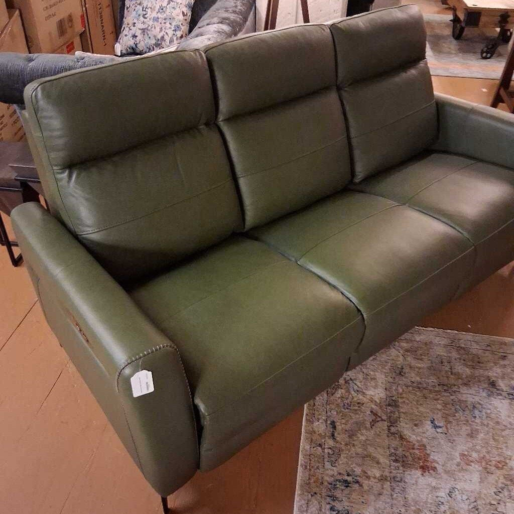 Green leather sofa in a room with a rug and boxes.