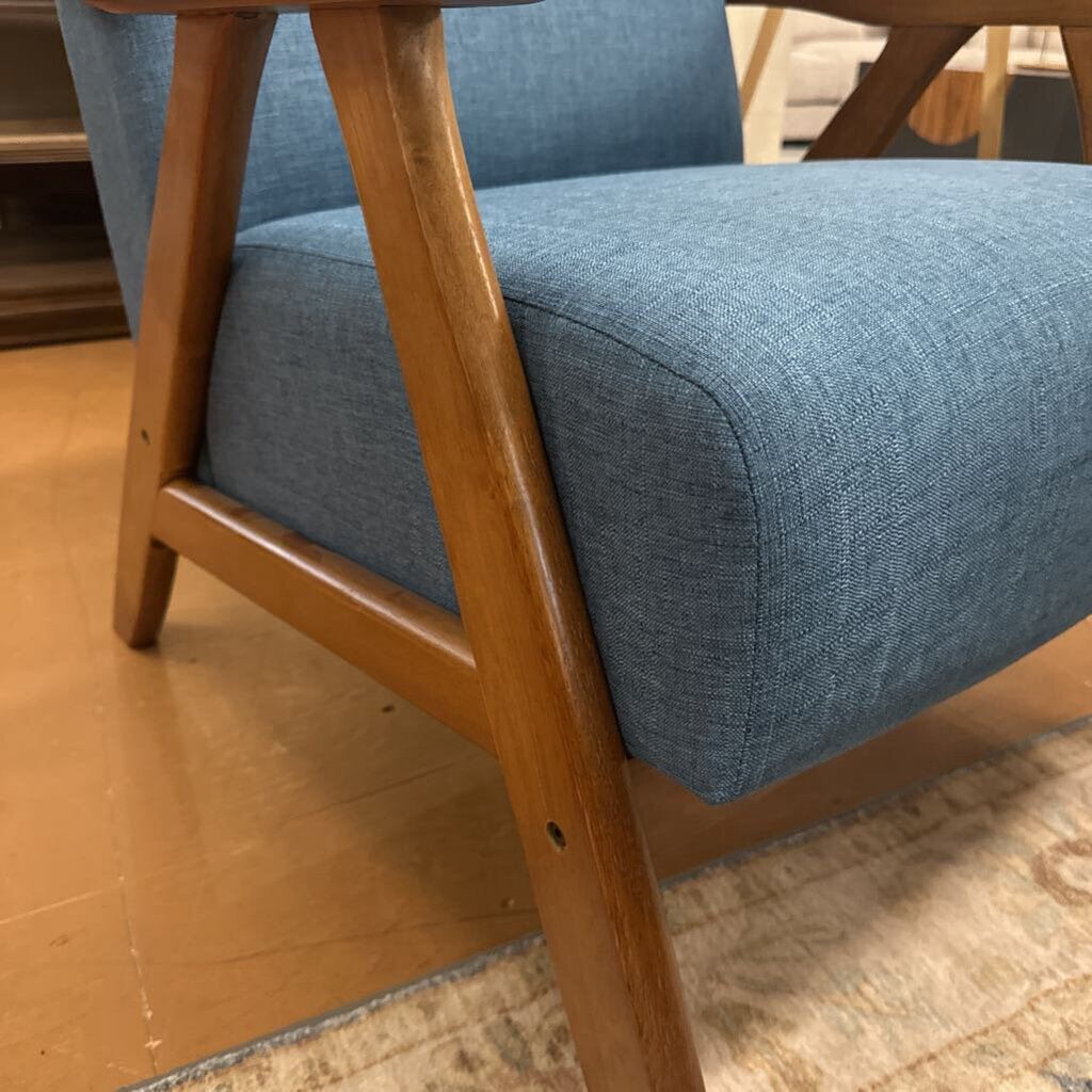Blue upholstered chair with wooden legs on a wooden floor.
