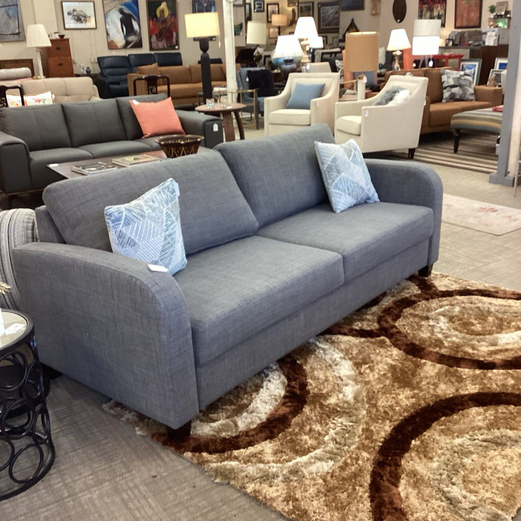 Gray sofa with decorative pillows in a furniture store setting