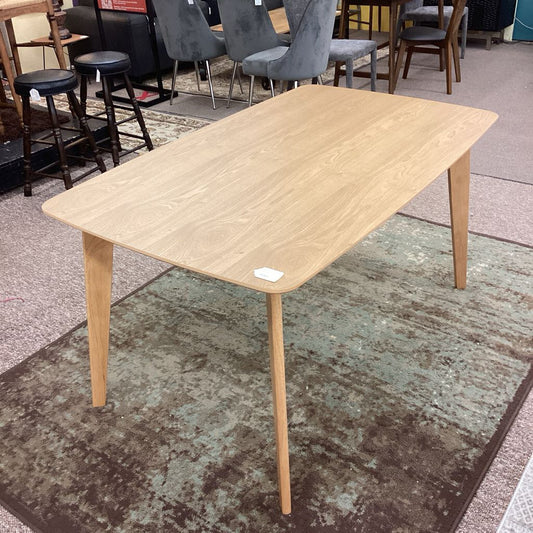 Wooden table on a carpeted floor with chairs in the background