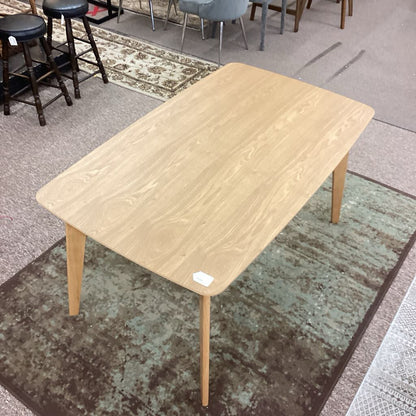 Wooden table on a carpeted floor with chairs in the background