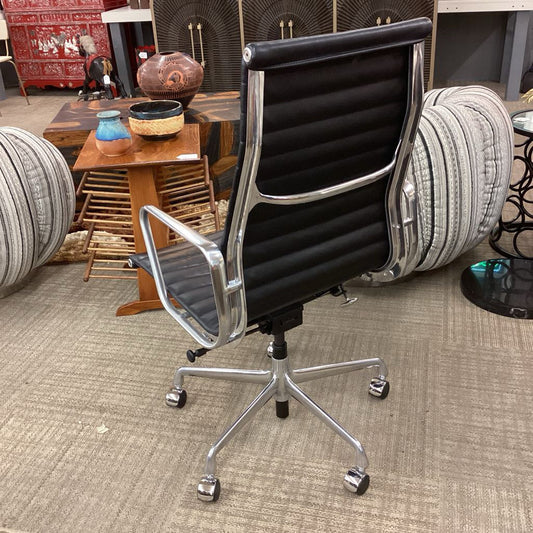 Black office chair with chrome frame in a room with furniture and decor.