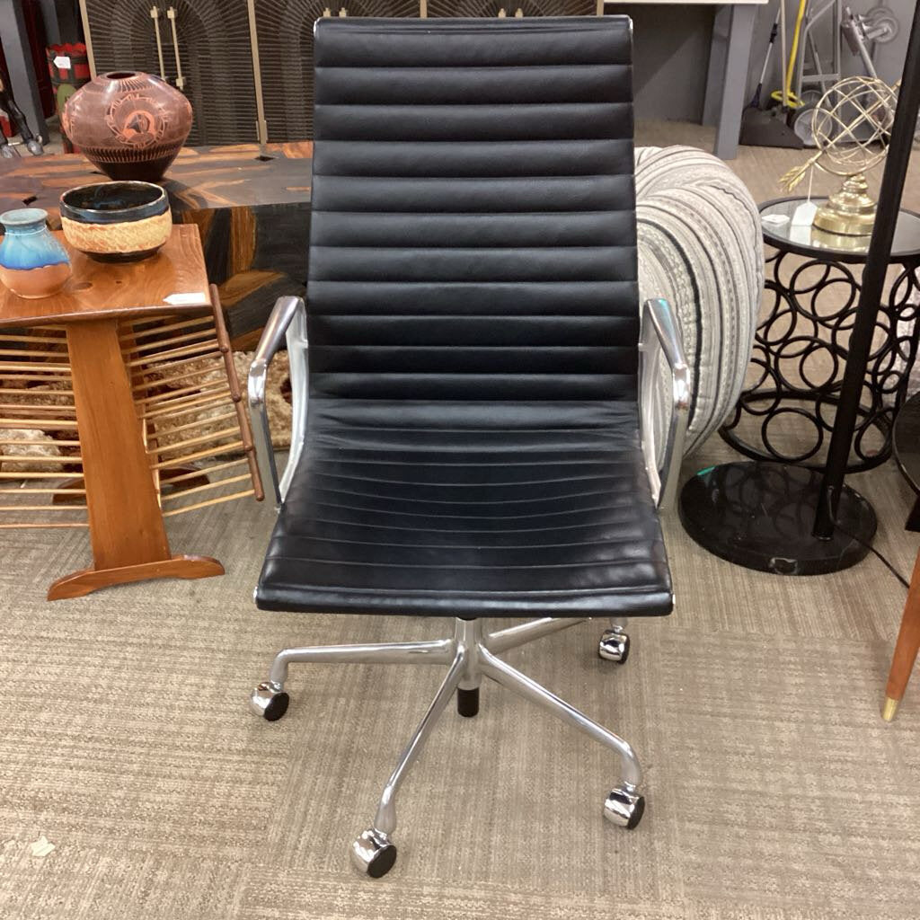 Black ribbed office chair with chrome base in a room with furniture and decor.