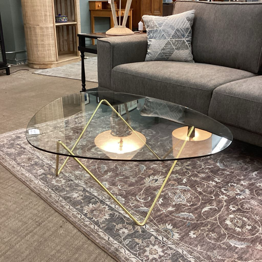 Glass coffee table with gold legs in a living room setting