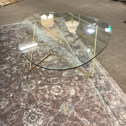 Glass coffee table with gold legs on a patterned rug