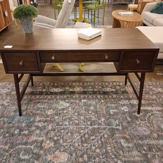 Wooden desk with drawers on a patterned rug in a room setting