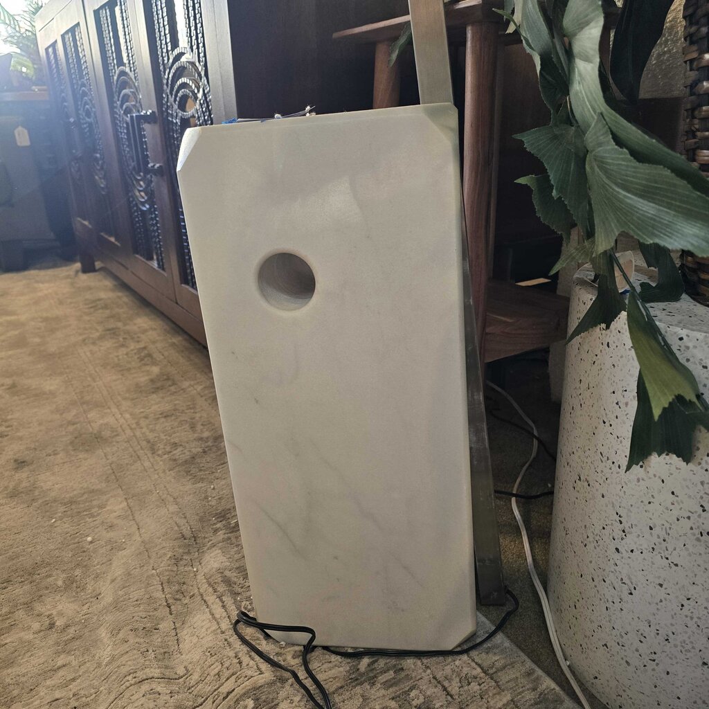 White electronic device on a stone floor with a plant in the foreground