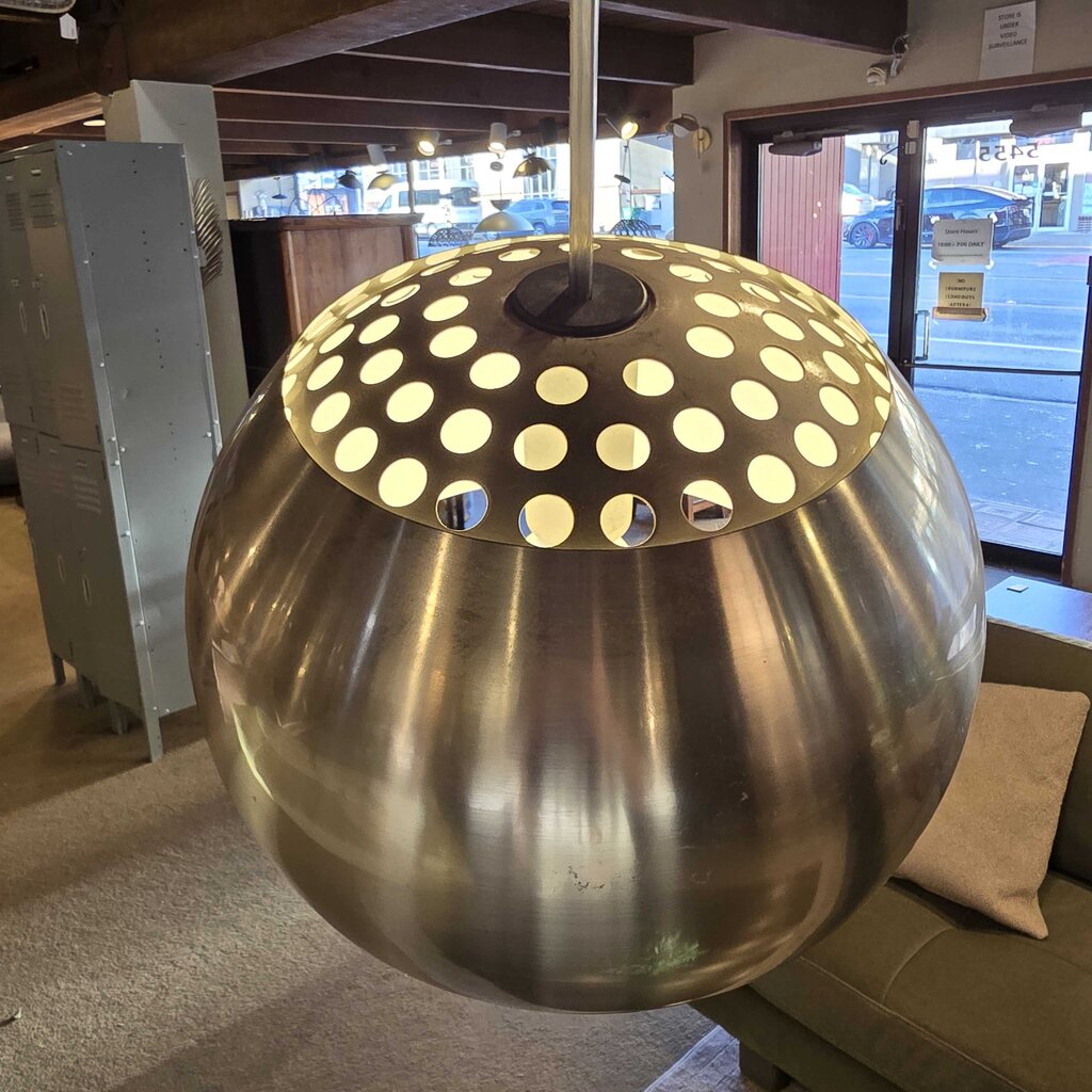 Decorative metal sphere with polka dot design on top, indoors.