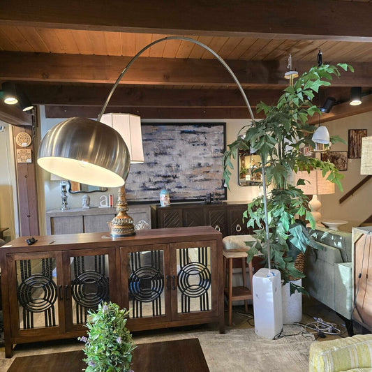 Living room with a large metallic floor lamp, wooden cabinet, and decorative plants.