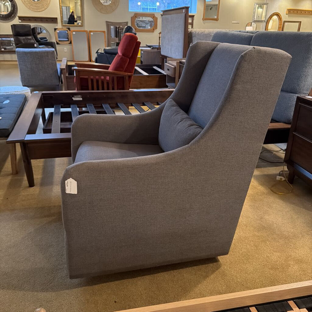 Gray armchair in a furniture store with other chairs and tables in the background.