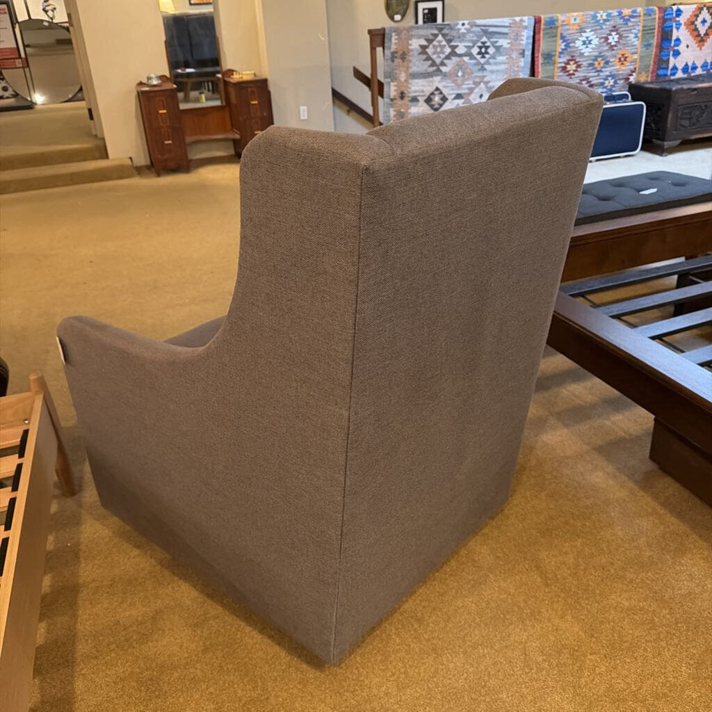 Brown upholstered chair in a room with furniture and decor.